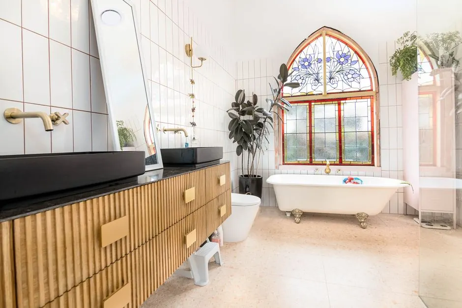 Bathroom with a clawfoot bath, stained glass window and fluted wooden vanity