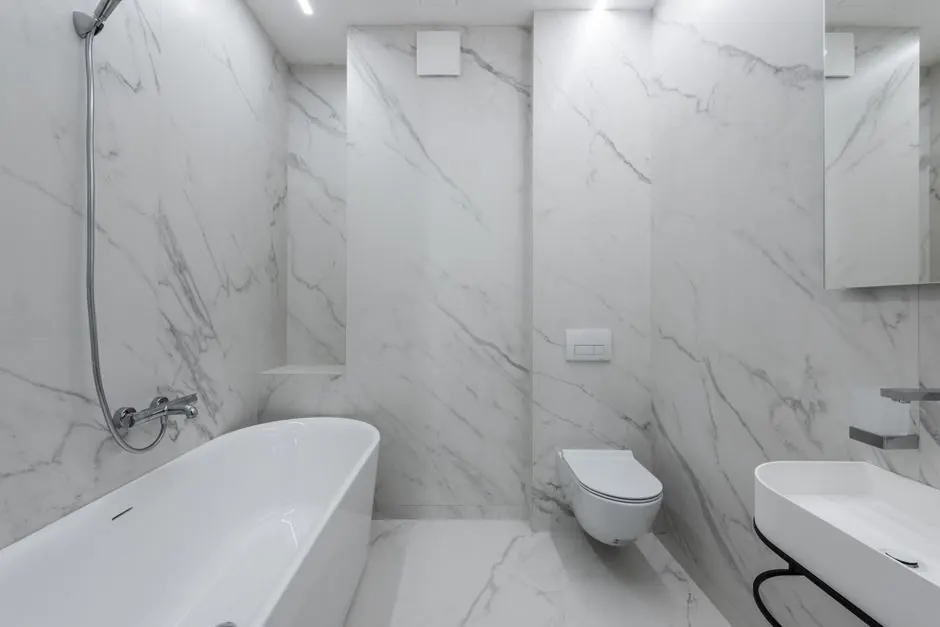 White marble-effect bathroom with a freestanding bath and wall-hung toilet