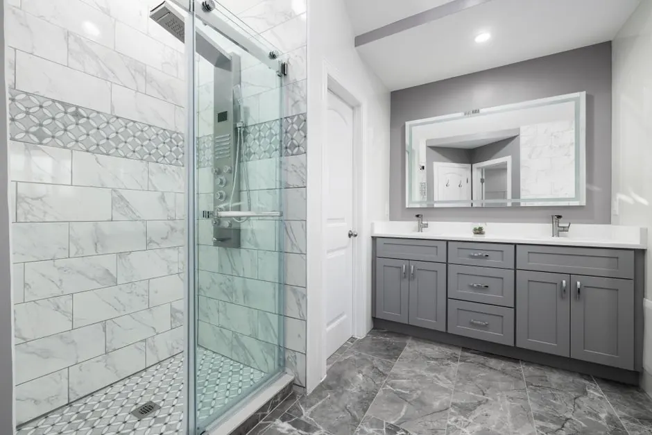 Walk-in shower with a sliding glass door beside a grey double vanity