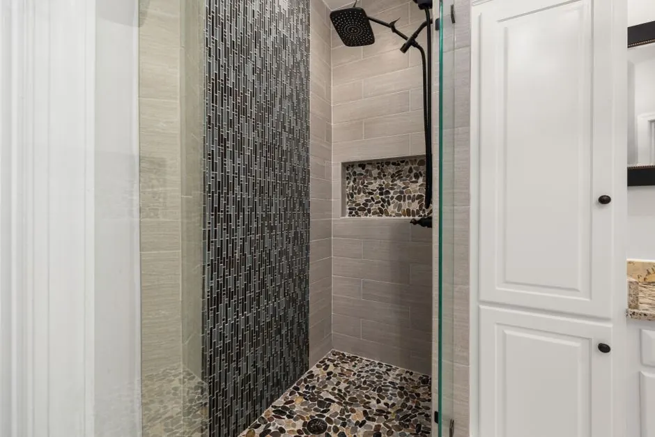 Walk-in shower with a pebble floor, mosaic feature wall and black rain shower head