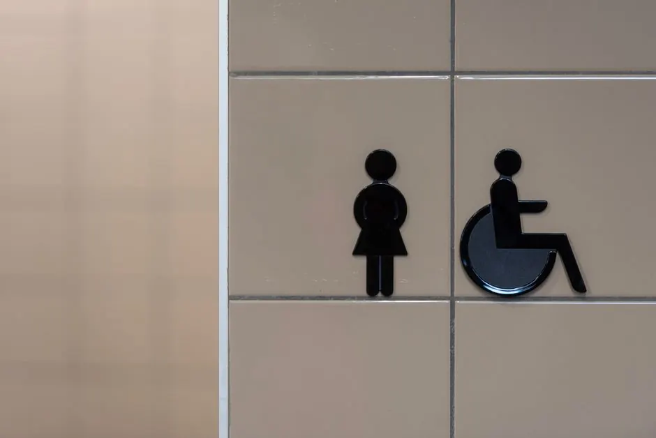 Accessible toilet sign with a wheelchair symbol on a tiled wall