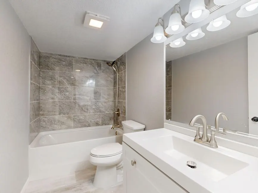 Bathroom with a tiled shower over the bath, toilet and vanity unit